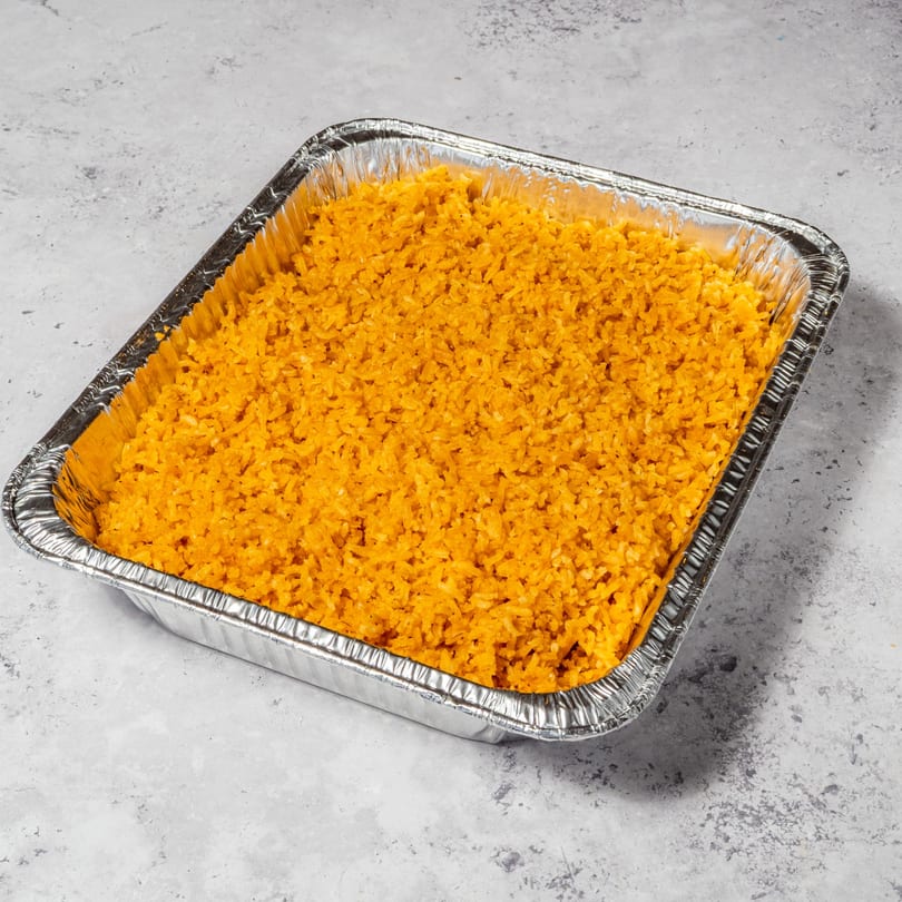 A large aluminum catering pan filled with bright orange Mexican rice, ready to serve.